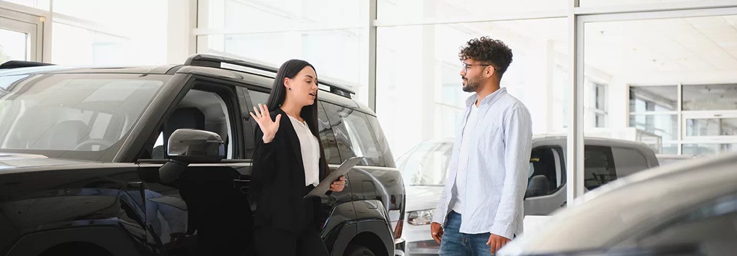 two people in car showrooom discussing a purchase of a new car