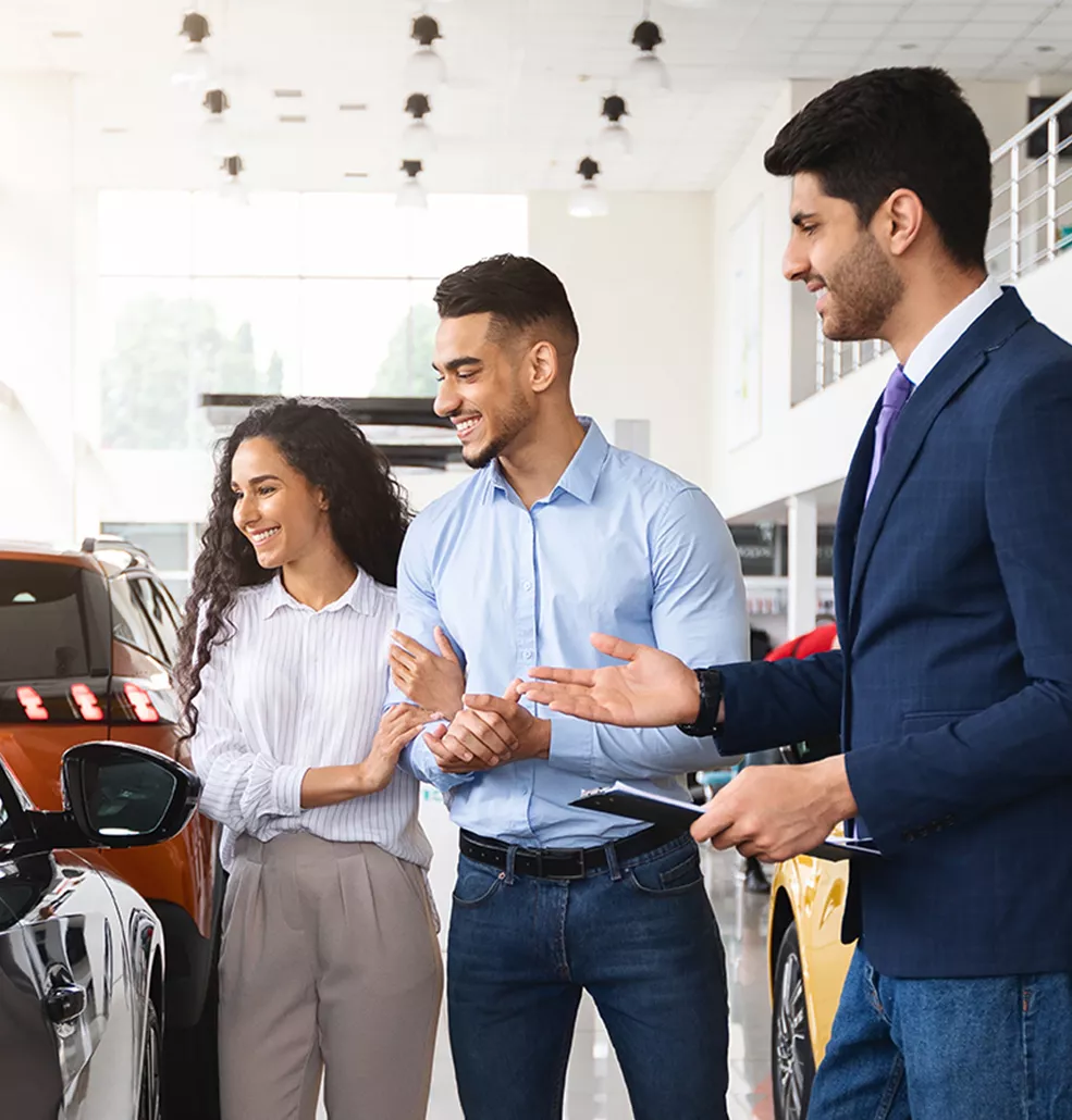 salesman showing man and woman a vehicle