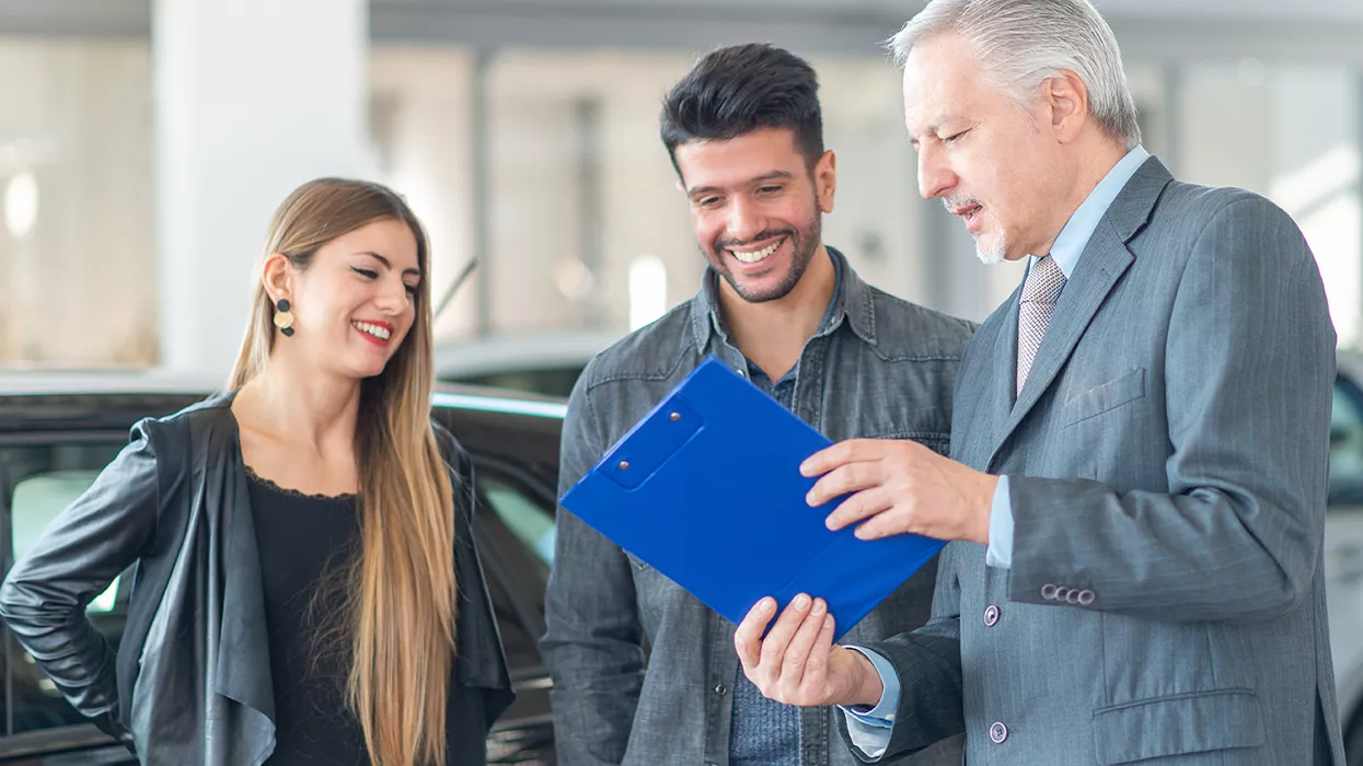 Car salesman showing a couple a clipbaord
