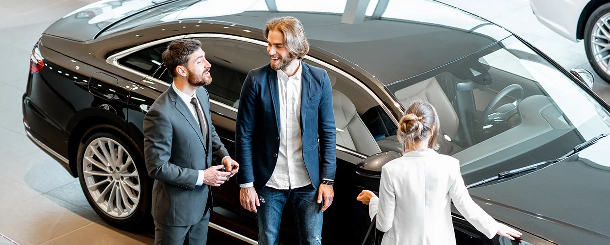 A group of three people poses in front of a car, showcasing a friendly and casual atmosphere.