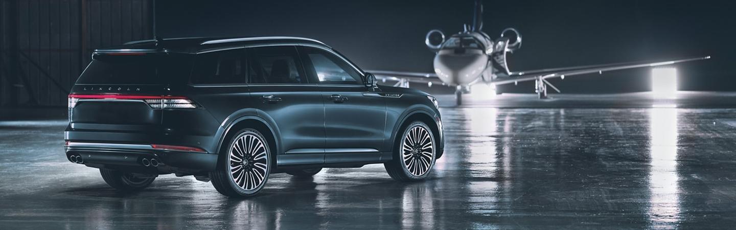 Rear angle profile of a gray Lincoln Aviator parked in an airport hanger