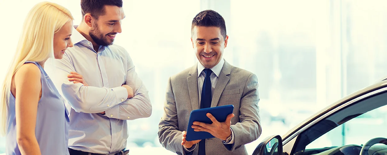 couple discussing car purchase with car salespersonin showroom