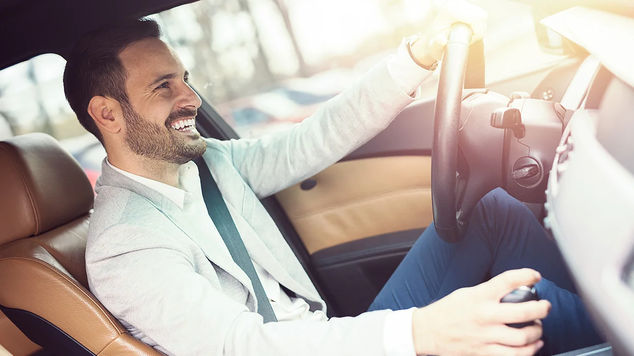 a happy person behind wheel of new car