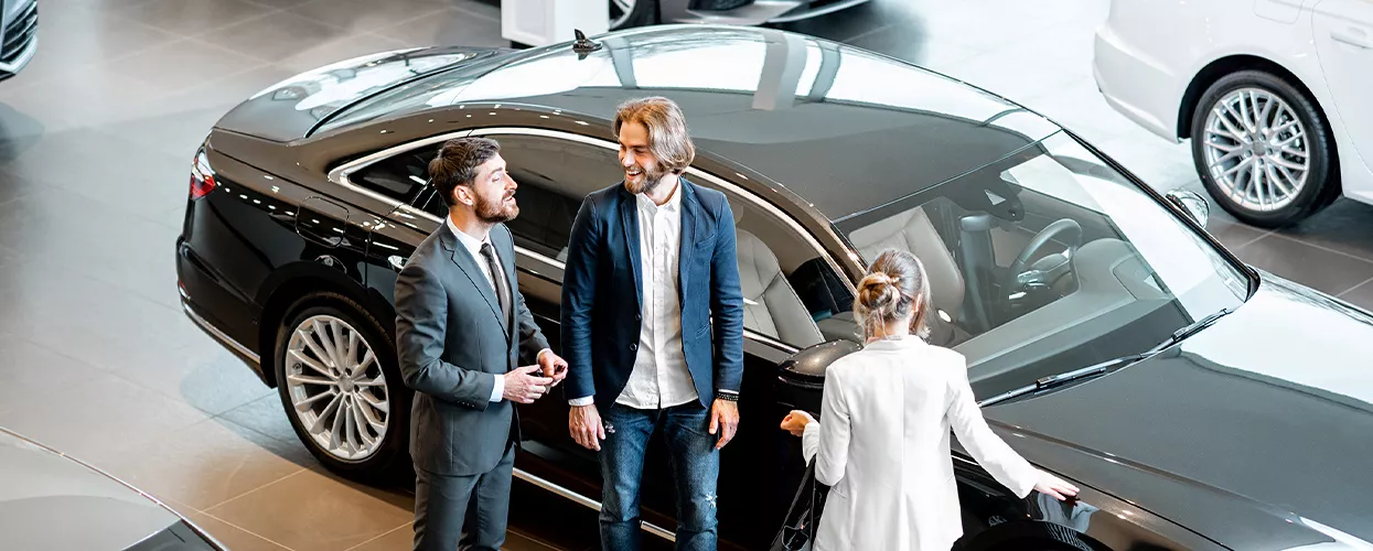 Three people talking in a car dealership
