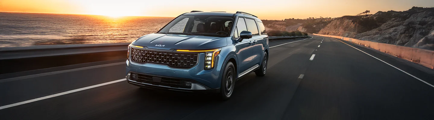 Kia SUV driving on a seaside road.