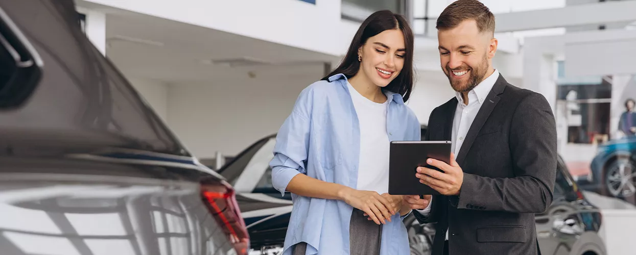 Car salesman showing a woman somehting on a clipboard in a car dealership