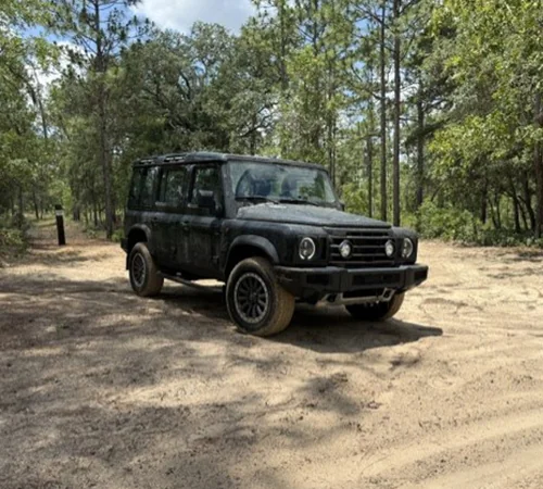 Front side view of parked green INEOS Grenadier in the woods