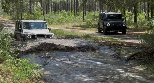 Two INEOS Grenadier driving though the woods one a drit path and the othere drining thought a mud bog