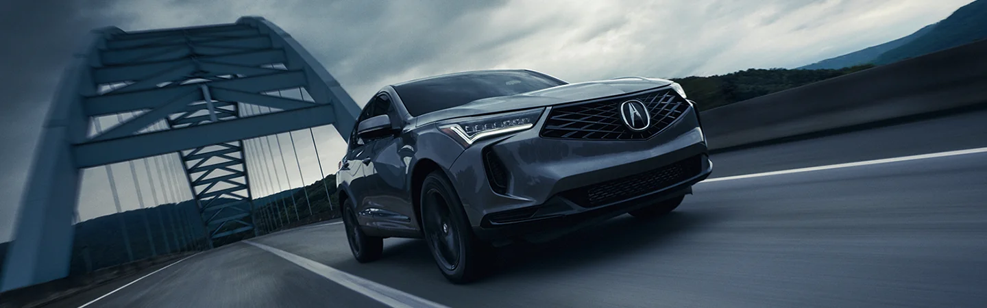Front view of a 2025 Acura RDX driving over a bridge