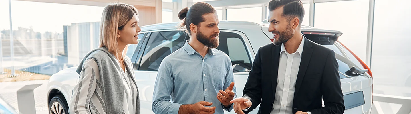 Customers speaking with a salesman about a car