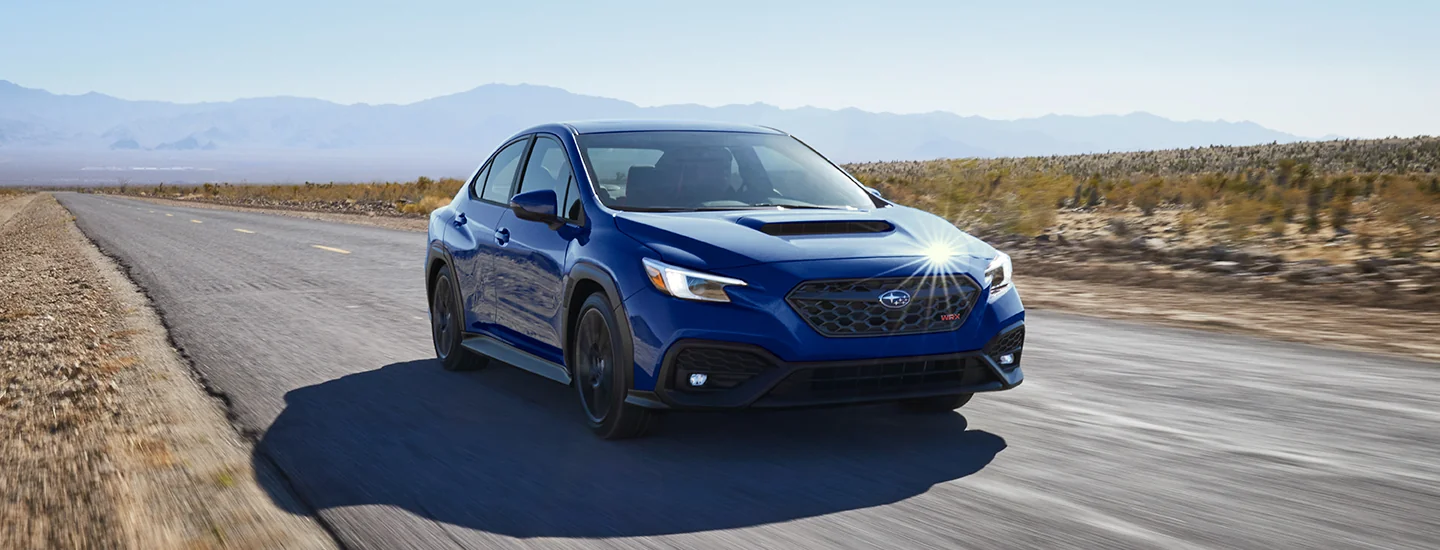 Front view of a blue 2025 Subaru WRX driving on a desert road