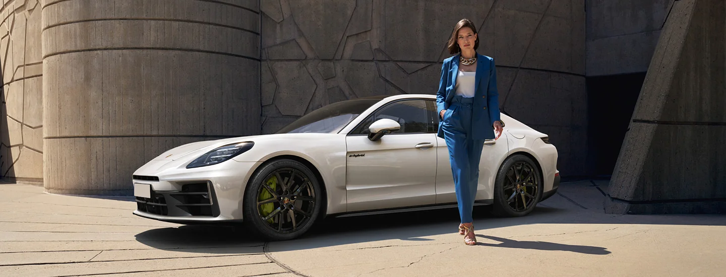 a parked white 2026 Porsche Panamera 4 E-Hybrid with person leaning the car walking