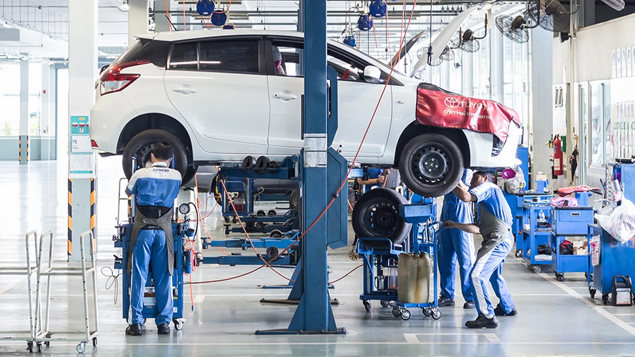 auto mechanics working in service bay with cars on lifts in view