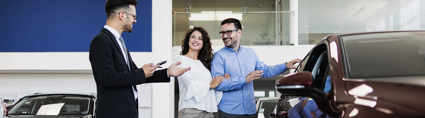 Sales person helping customers look at a new car