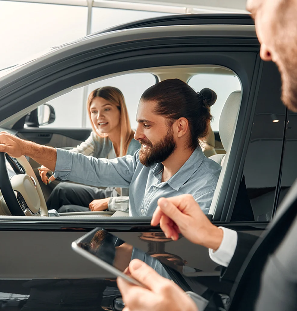 couple speaking with car salesperson from inside car