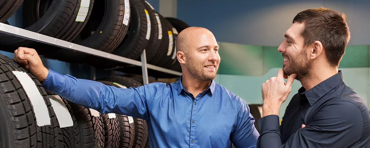 Service mechanic showing a customer a row of tires
