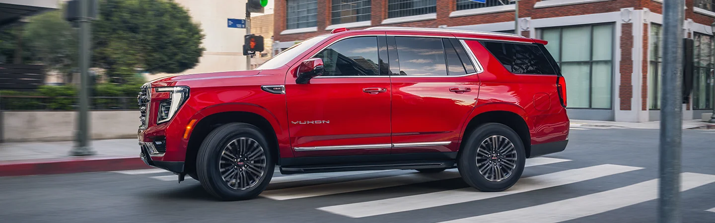 red 2025 GMC Yukon driving in the city