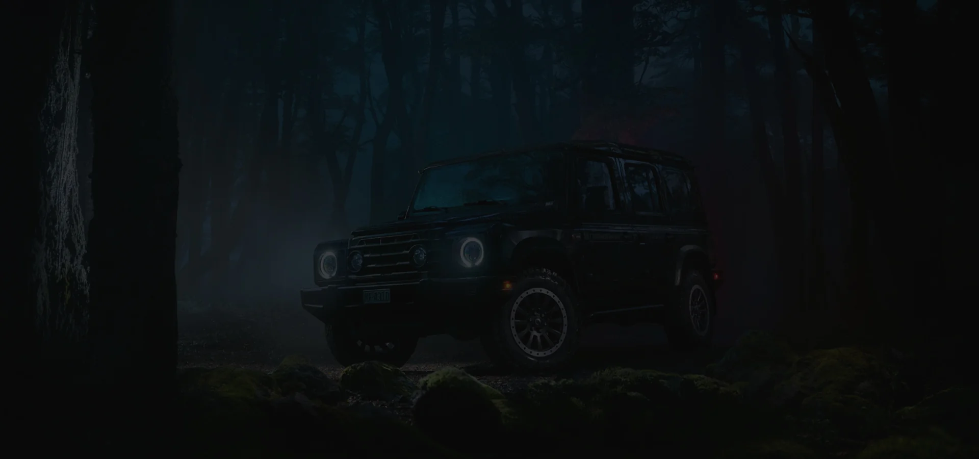 Dark iamge of a INEOS Grenadier SUV parked in the woods at night