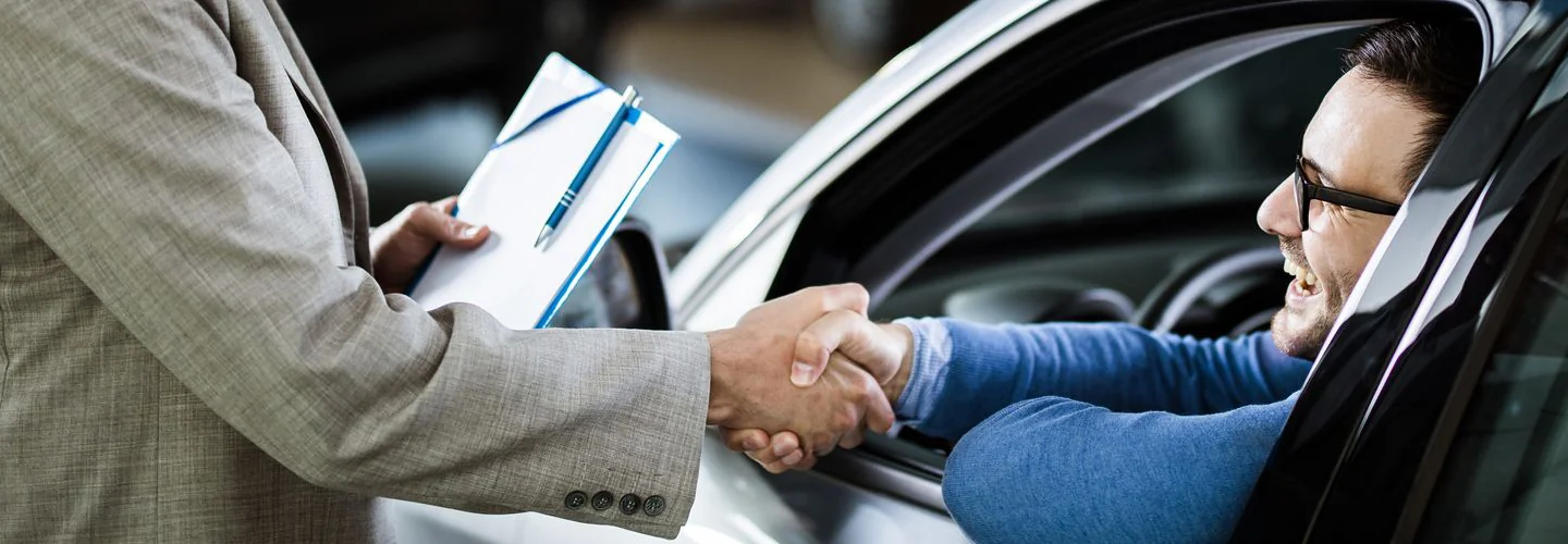 Driver in car shaking hands with another person