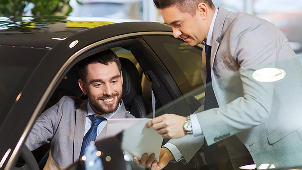 car salesperson showing lease details to customer sitting in car
