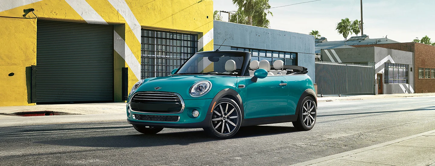 blue 2025 MINI Cooper Convertible parked in city by colorful painted buildings