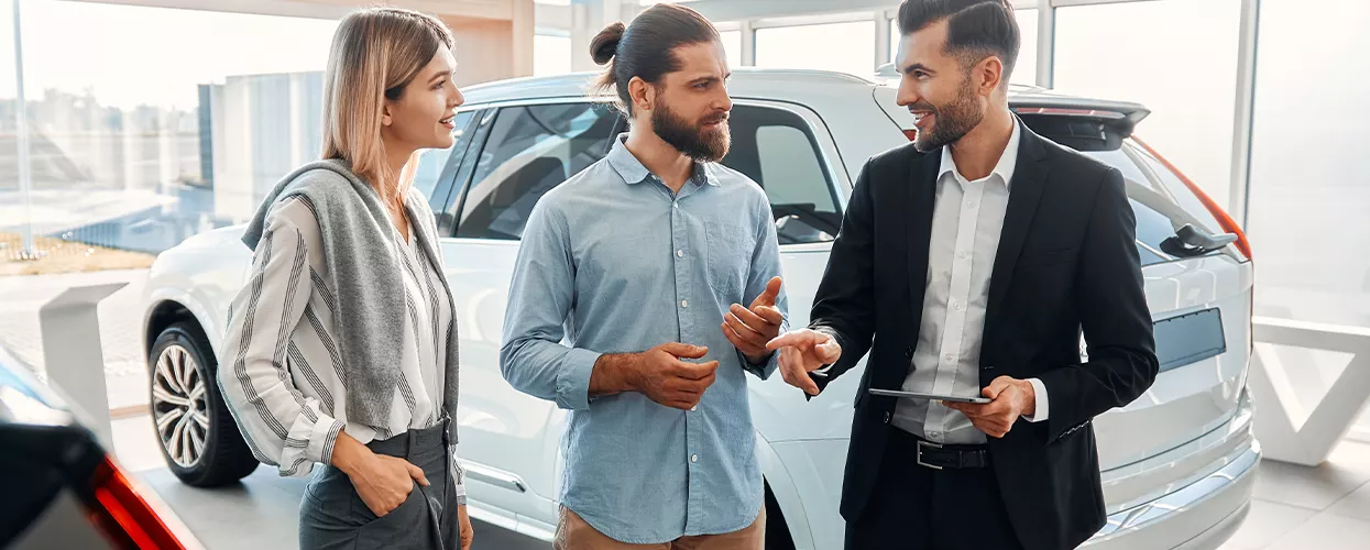 Couple talking to a car salesman in a dealership