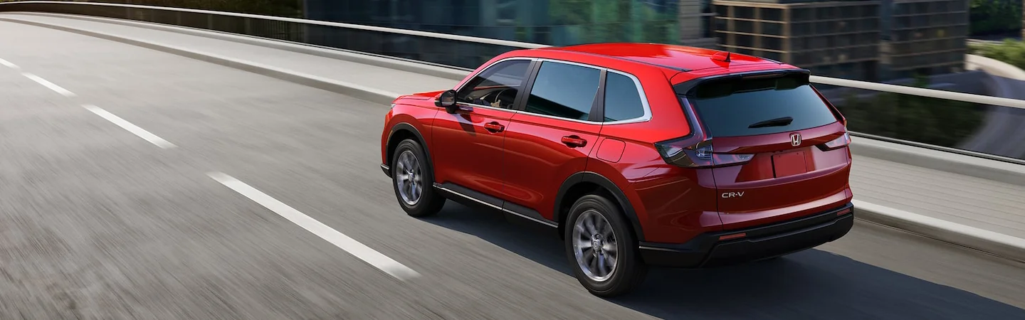 Back side view of a red 2025 Honda CR-V driving on a freeway