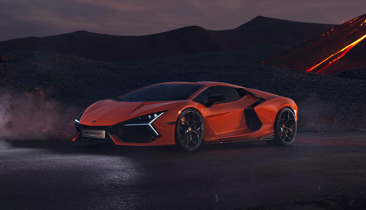 Orange Lamborghini Revuelto parked on a mountain road at dusk