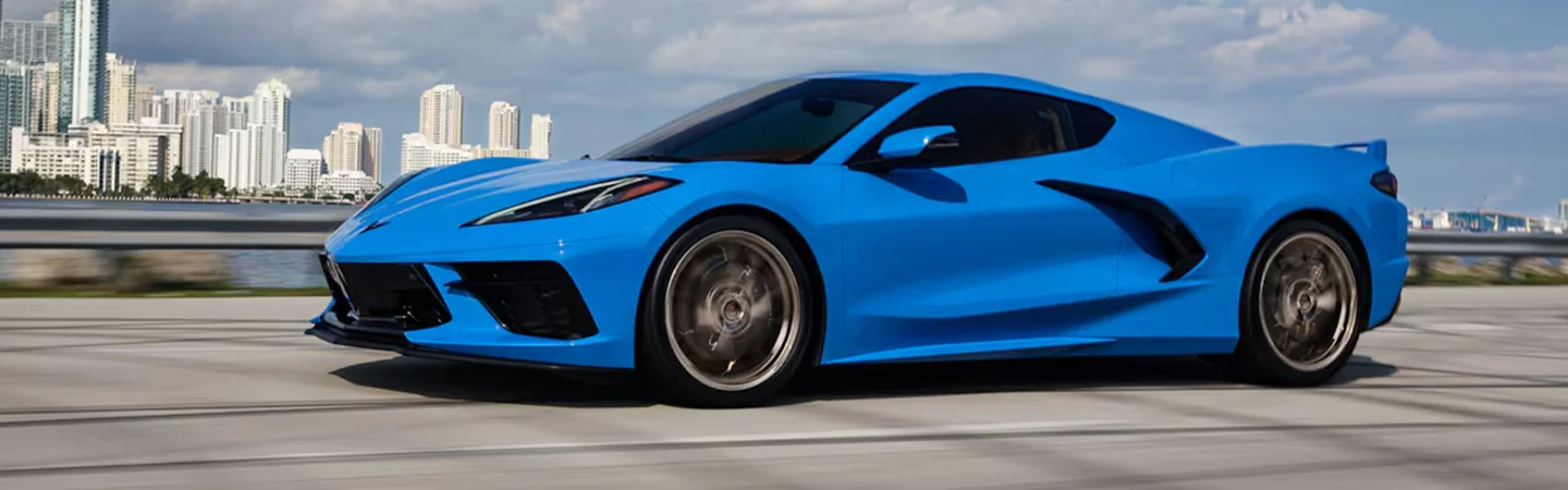 Side view of a blue 2024 Chevrolet Corvette Stingray driving on a street