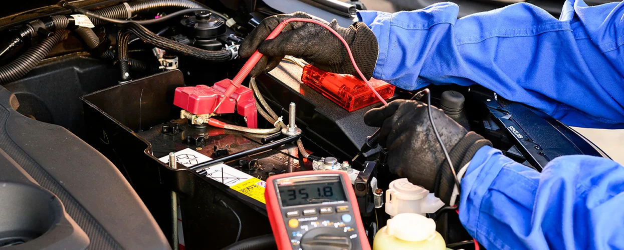 auto mechanic hands in view working on an engine testing voltage