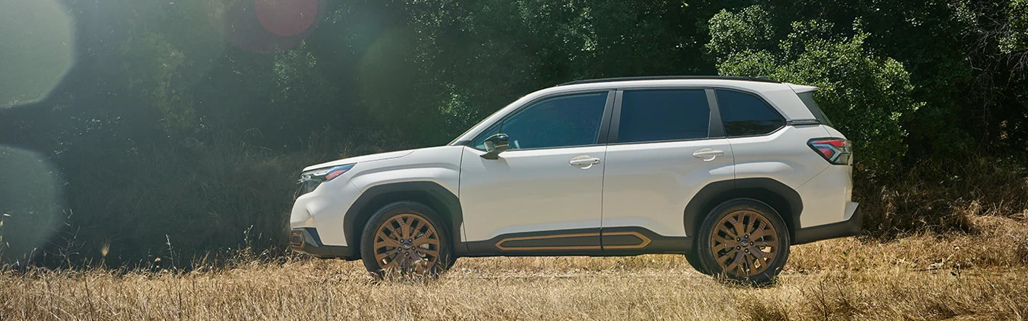 Side view of a white 2025 Subaru Forester driving in a neighborhood in Nederland, TX