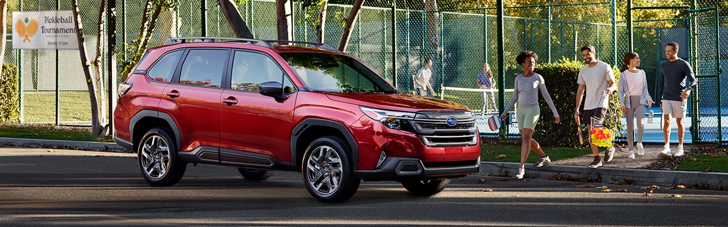 Side view of a parked red 2026 Subaru Forester with people walking to the car after oickleball