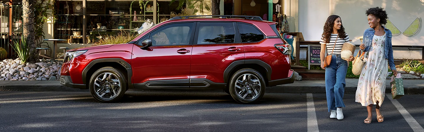 Side view of a parked red 2026 Subaru Forester on a city street