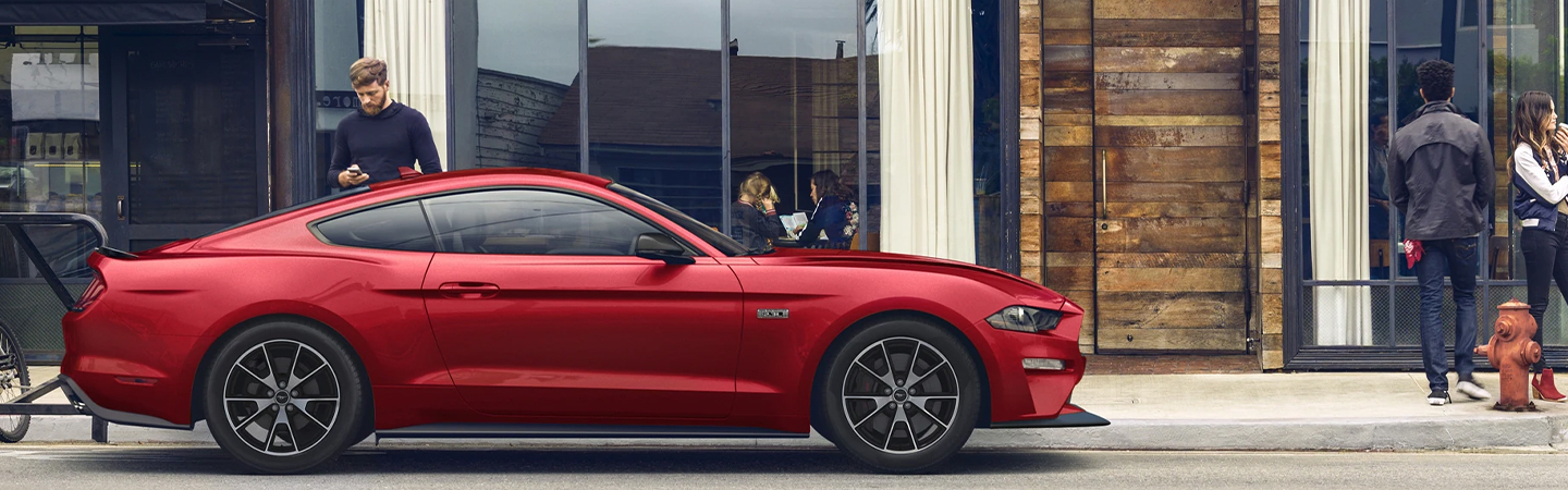 2023 Ford Mustang parked in a town with people walking around