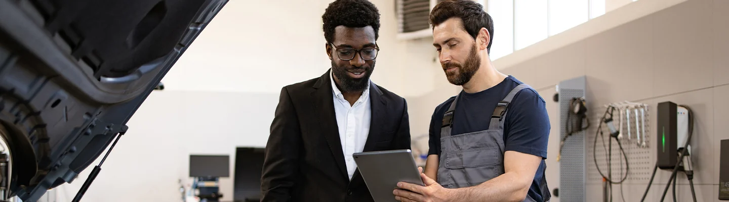 mechanic speaking with another person holding a clipboard about car repair