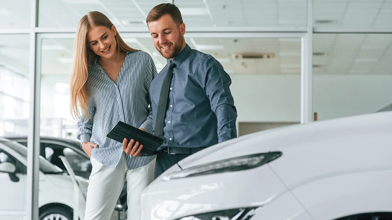 car salesperson showing a car's features to customer in showroom