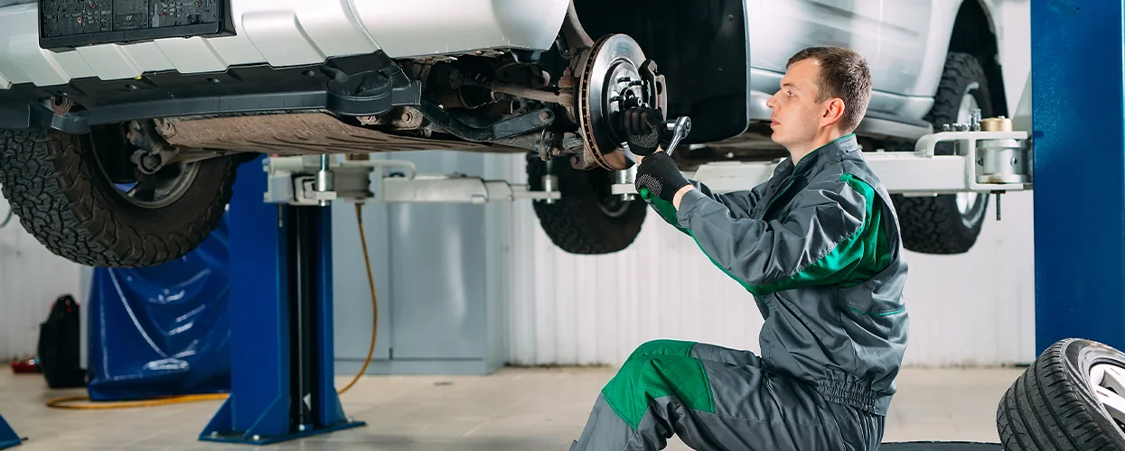 car mechanic working on wheel of car on lift