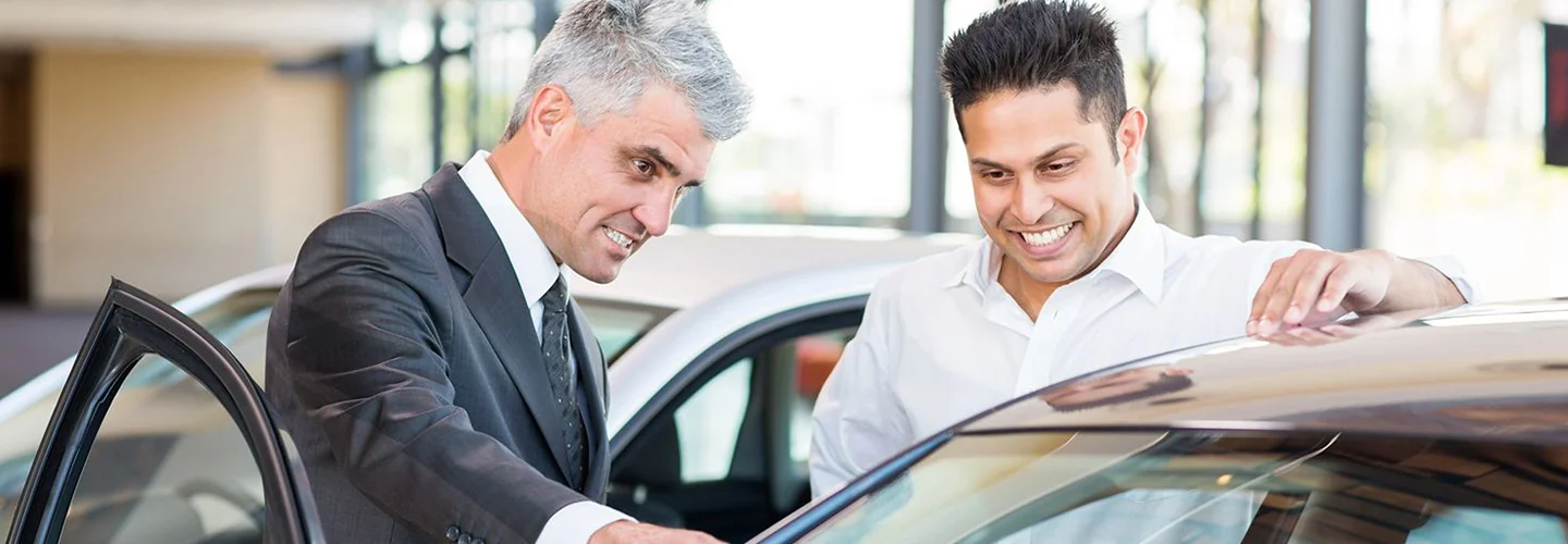 Sales person helping customer look at a new car