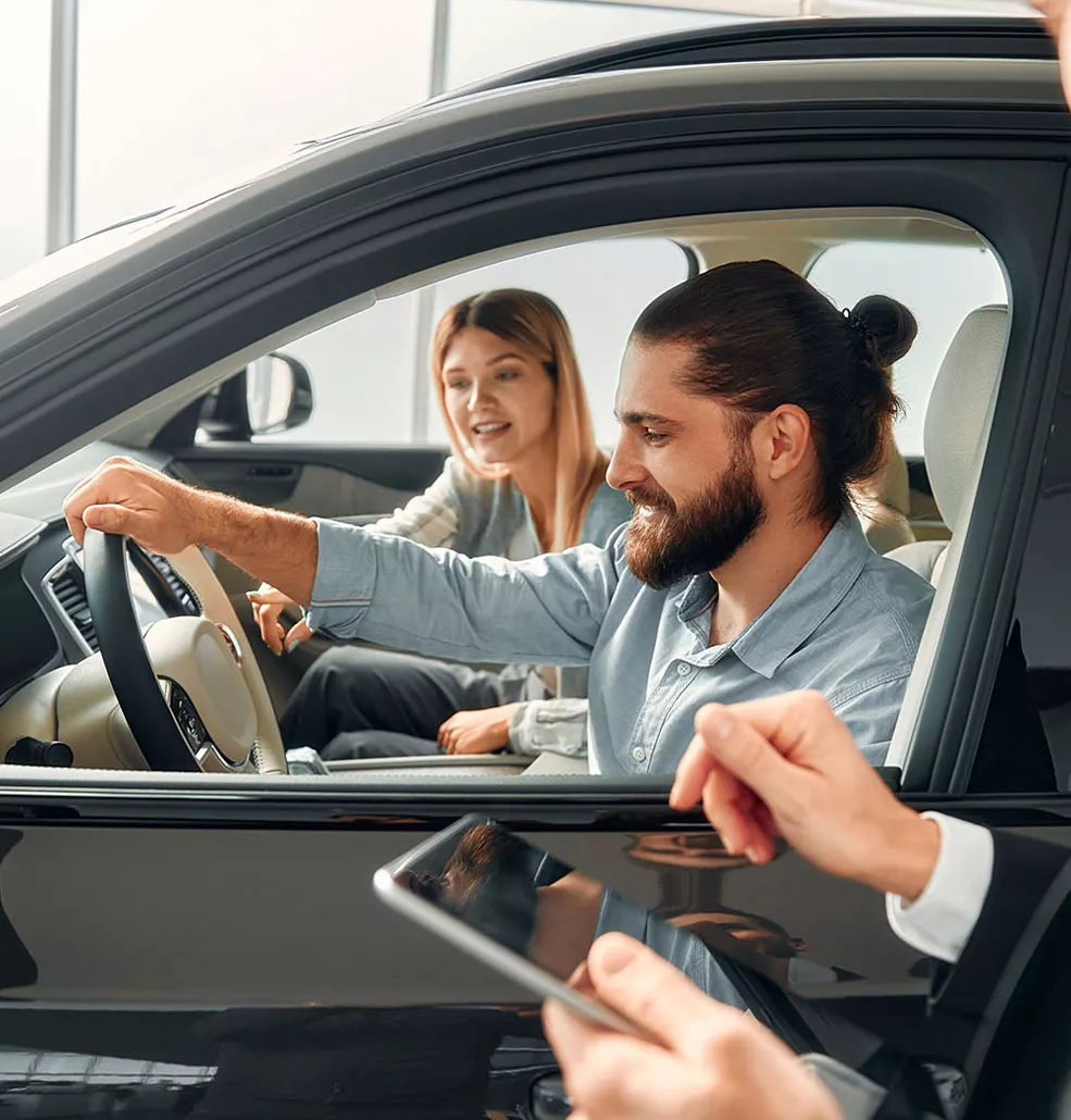 2026 Dodge Charger interior with man and woman sitting in the front seats with the salesman standing outside holding a tablet