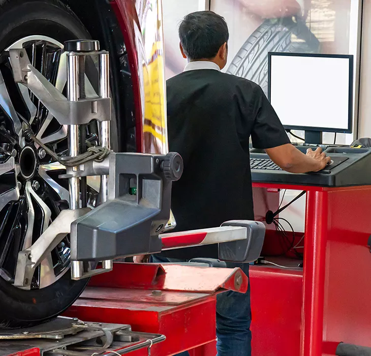 mechanic in the shop room running a diagnosis of a vehicle on the computer