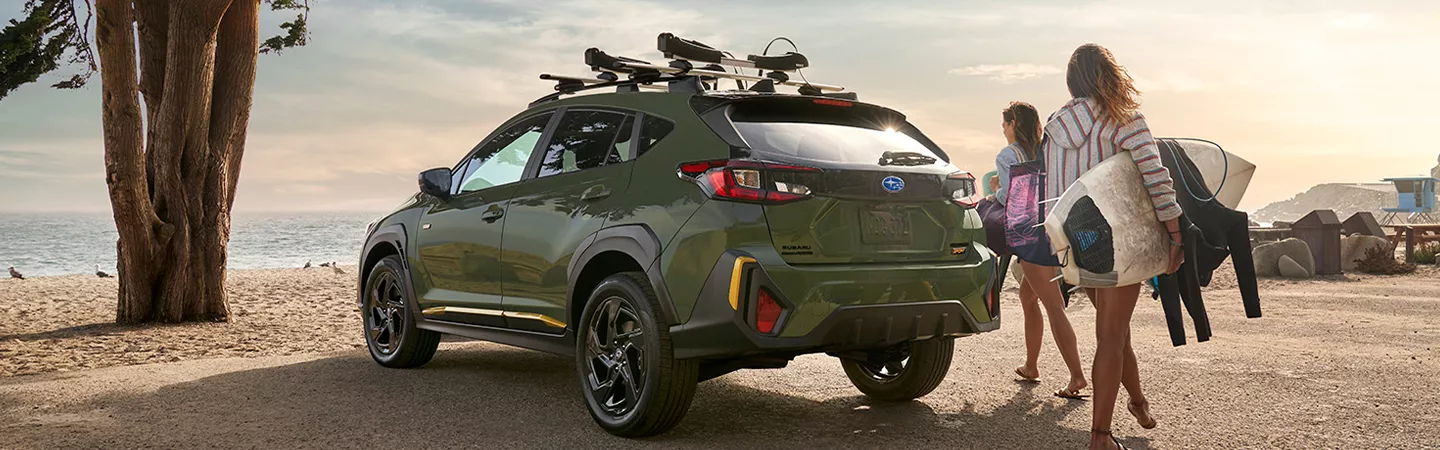 Surfers walking on a beach behind their parked 2026 Subaru Crosstrek