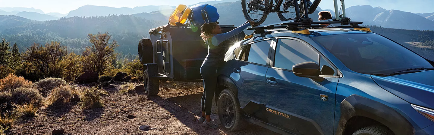 Person loading bikes onto the roof racks of a 2026 Subaru Crosstrek