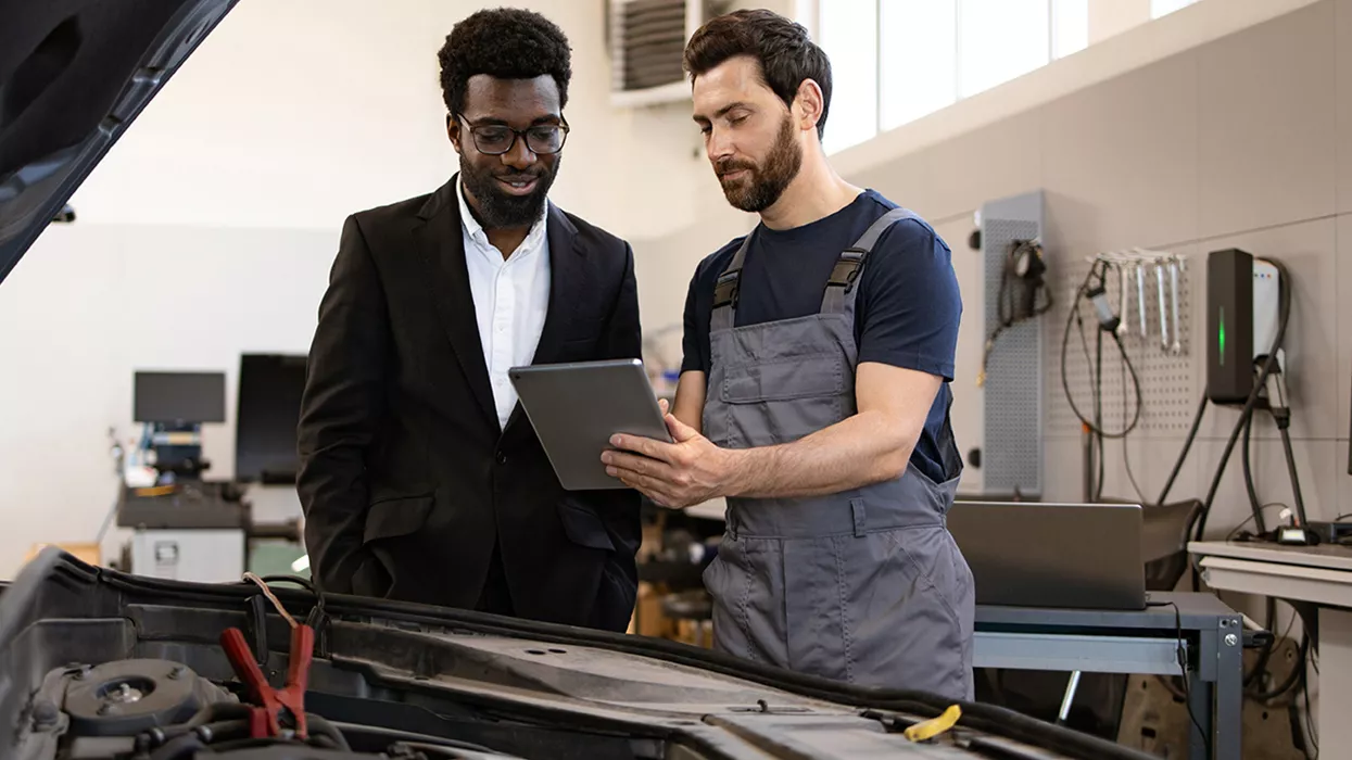Mechanic talking to a car owner, holding a tablet