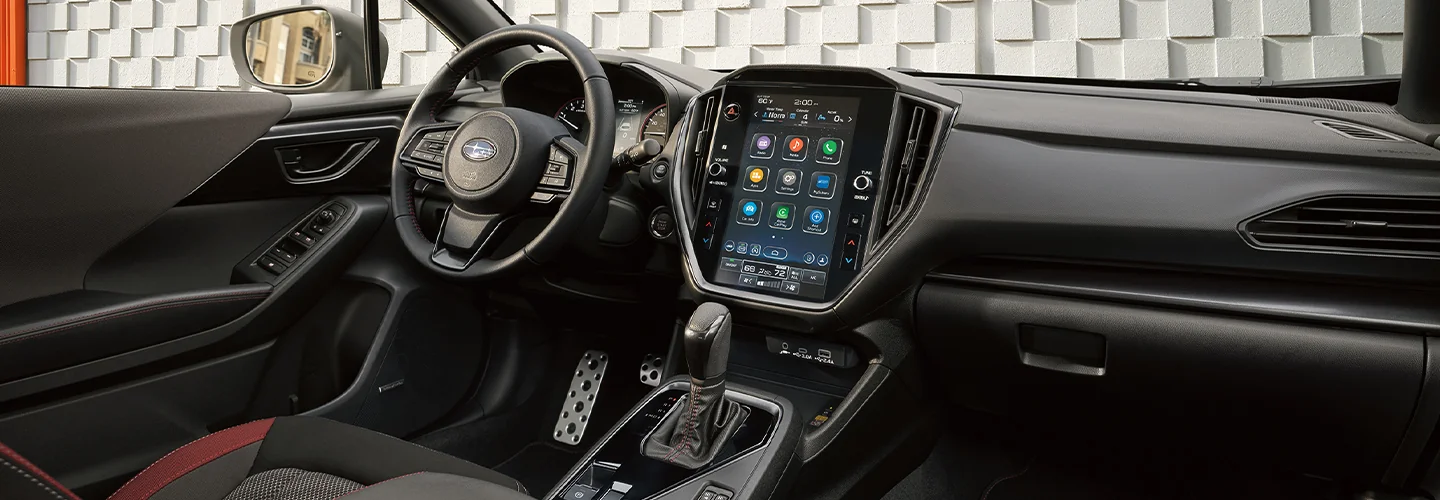 Interior view of the dashboard and tech of a Front view of a parked black 2026 Subaru Impreza in front of a dog spa