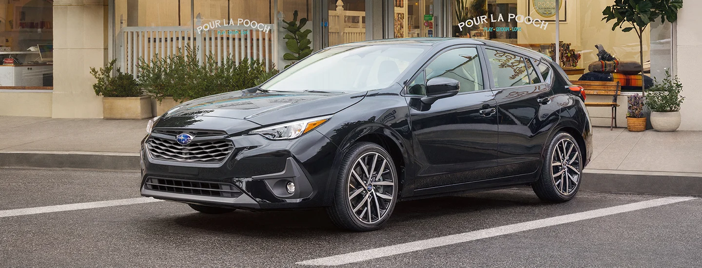 Front view of a parked black 2026 Subaru Impreza in front of a dog spa