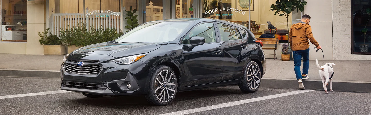 Front view of a parked black 2026 Subaru Impreza in front of a dog spa