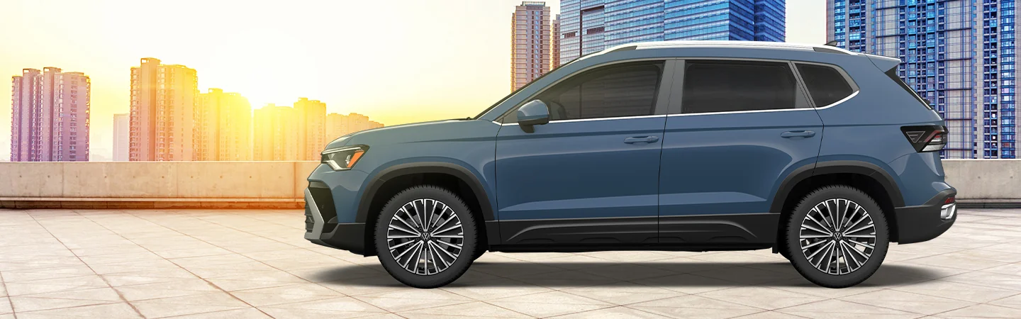 Side view of a parked 2025 Volkswagen Taos with a city in the background