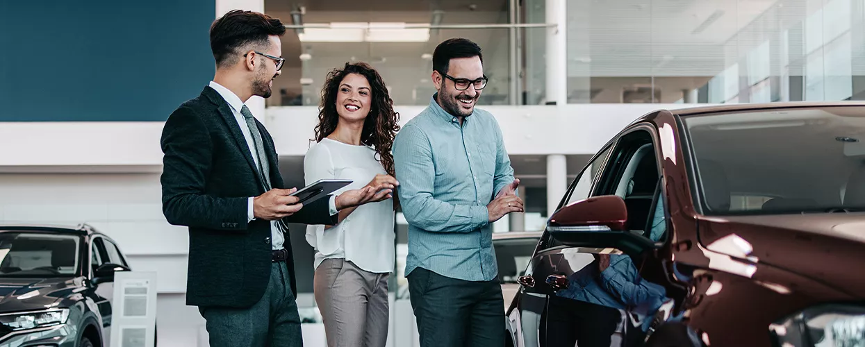 A car salesman showing a couple a new car