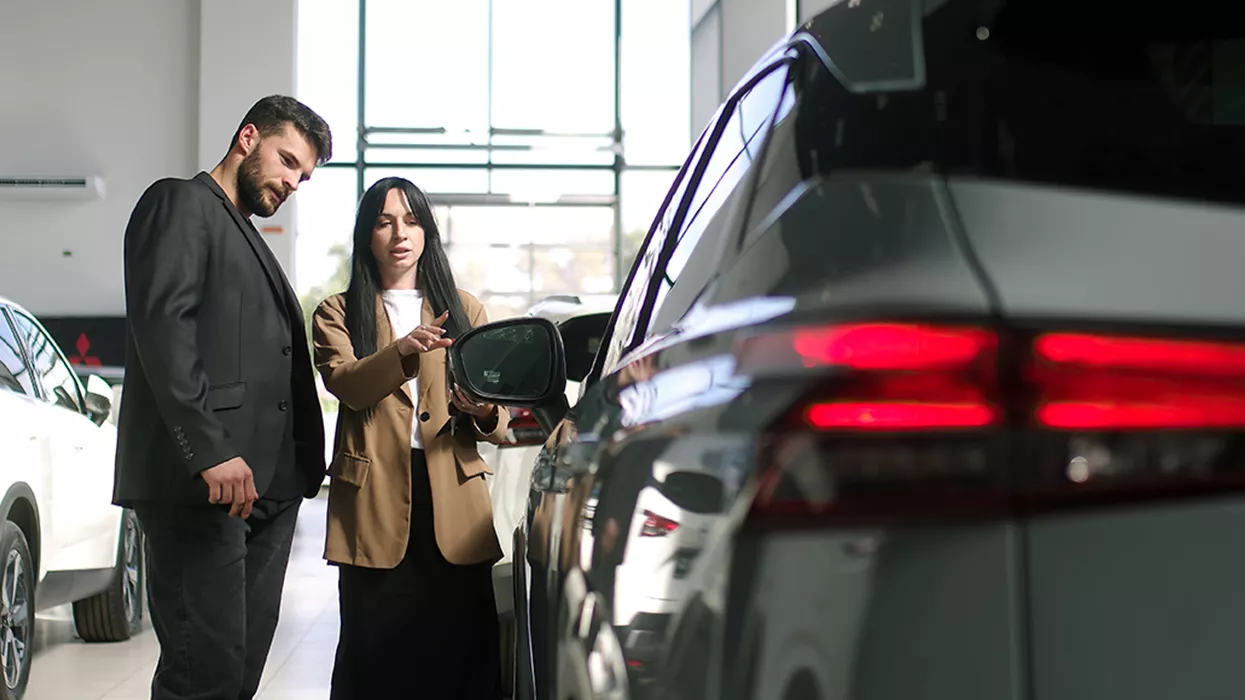 Car saleswoman showing someone a new car in a dealership