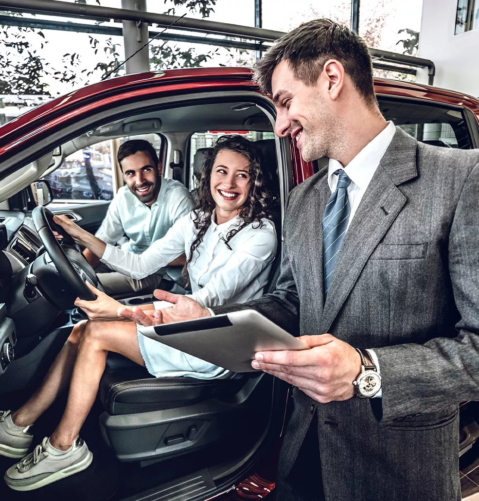 Couple sitting in a new vehicle at a car dealership